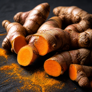 Fresh turmeric root on dark slate — knobbly rhizomes with vivid orange interior